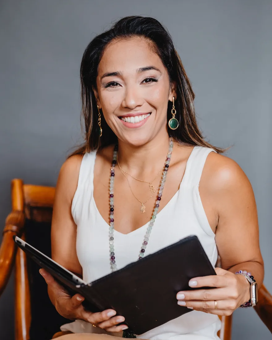 Retrato de Eliany Uemura, terapeuta holística e aromaterapeuta, sorrindo e segurando um caderno